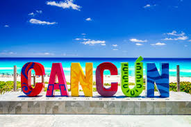 Iconic colorful Cancun letters at Playa Delfines with turquoise waters and white sandy beach in the background.