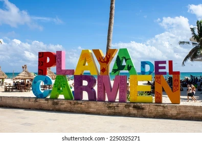 Iconic colorful Playa Del Carmen letters at Playa Delfines with turquoise waters and white sandy beach in the background.