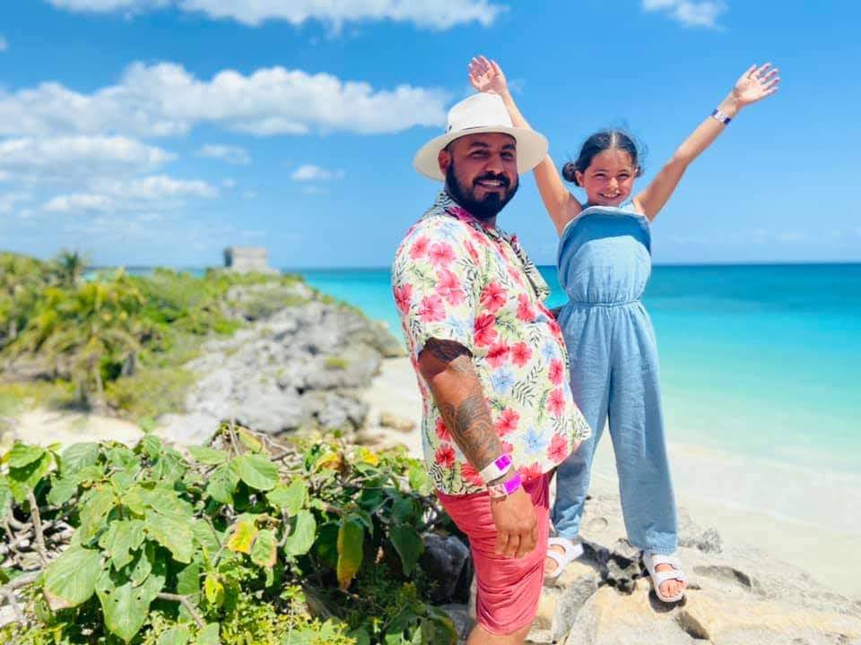 Family picture with the Mayan Ruins and the caribean ocean in the background.